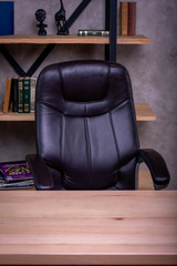  working place in the office leather chair and wooden table on the background of a shelf with books