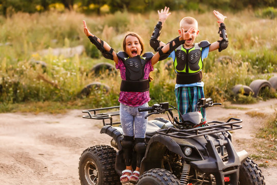 Happy little children playing on road at the day time. They driving on quad bike in the park. Kids having fun on the nature. Concept of happiness. © Angelov