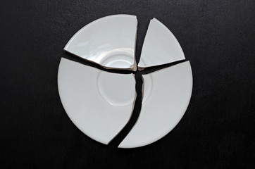 Broken plate on a black background, a try to restore the whole from the pieces