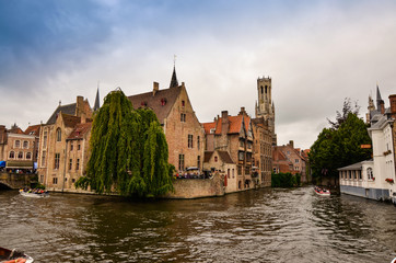 Fototapeta na wymiar Bruges, flanders belgium.August 2019.Rozenhoedkaai is a landmark of the historic center, the most loved by tourists: the canal that curves around the house with the willow and the bell tower.