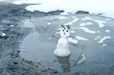 snowman in puddle. bad warm rainy winter weather. melted snowman. anomaly weather concept. copy...