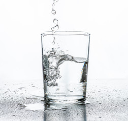 Water being poured into a glass. White background.