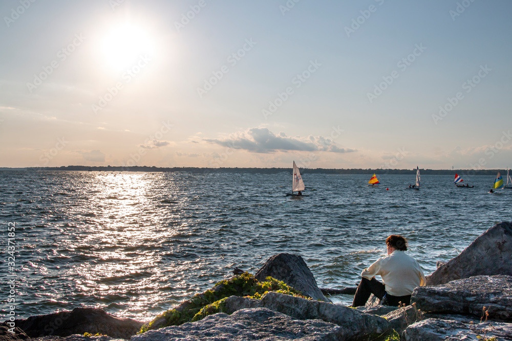 Wall mural Man sitting by the ocean watching the waves