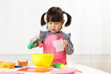 toddler girl pretend play food preparing role at home agianst white background