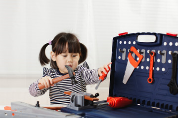 toddler girl pretend using DIY tool at home against white background