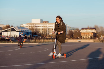 Happy girl rides on kick scooter on warm spring evening.