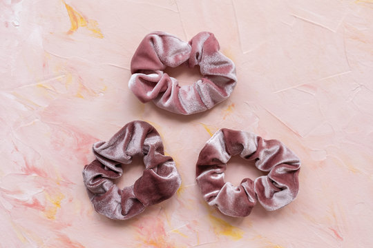 Three trendy velvet scrunchies on pink background. Diy accessories and hairstyles concept, copy space