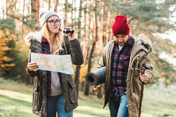 Travel couple with map, compass and backpack in the forest. Freedom and active travel concept.