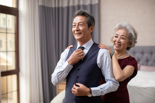 Happy senior Chinese couple getting dressed at home