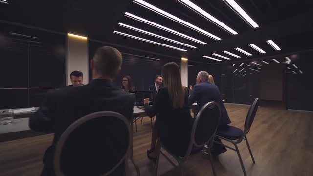 The group of people sit at the table and discuss business project. slow motion