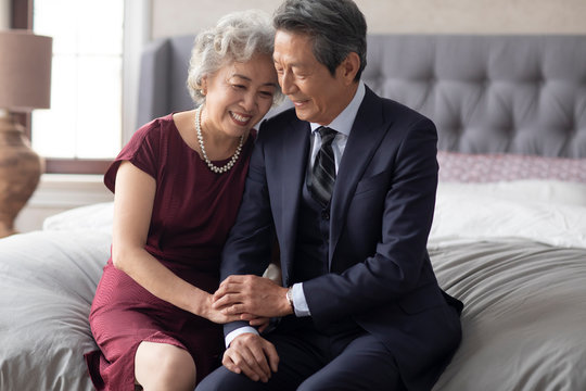 Happy senior Chinese couple enjoying their love in bedroom