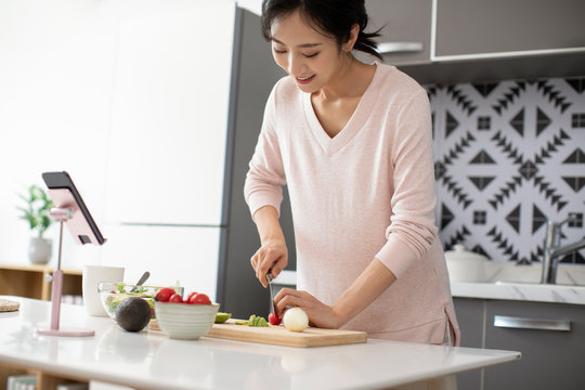 Happy Young Chinese Woman Cooking In Kitchen