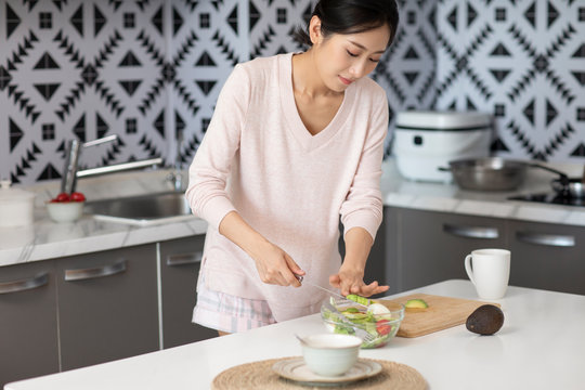 Young Chinese woman cooking in kitchen