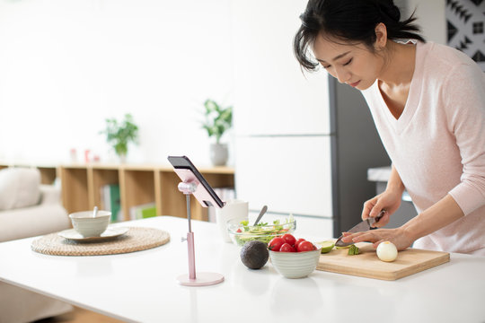 Happy Young Chinese Woman Cooking In Kitchen