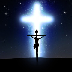 silhouette of the cruzifix in front of a huge light cross at night