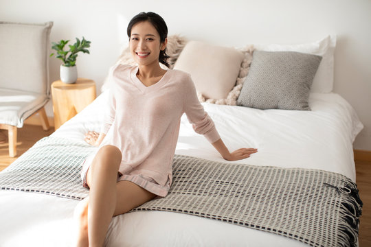 Happy young Chinese woman relaxing in bedroom
