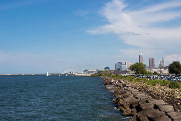 Beautiful summer landscape, which depicts the rocky shore of the lake, waves on the water and in the distance are the pain of skyscrapers. View of city of Cleveland,Ohio,USA from the lake Erie