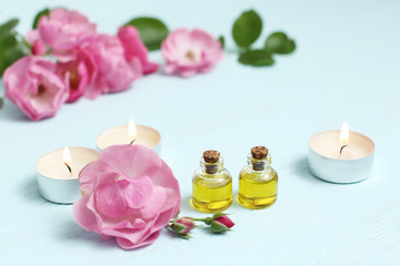 Rosehip cosmetic oil in mini bottles and pink rosehip flowers. Spa treatments for relaxation.