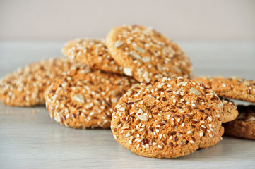 Oatmeal cookies with grains of flax, sunflower and sesame seeds on a wooden background. Selective focus.