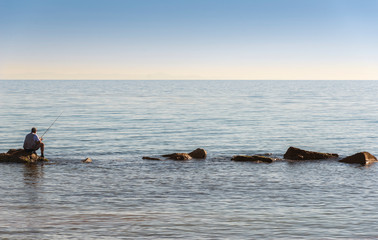 A fisherman fishes at the mouth or delta of the Ebro river, in Tarragona (Spain), during the sunset...