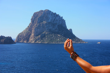 Caucasian girl relaxes by doing Buddhist meditation on a cliff in front of the islet of Es Vedra in...