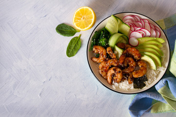 Honey soy shrimp rice bowl with spinach, radish cucumber, seaweed and avocado. View from above, top view