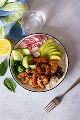 Honey soy shrimp rice bowl with spinach, radish cucumber, seaweed and avocado. View from above, top view