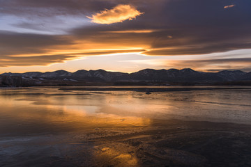 Obraz premium Sunset at Winter Lake - A golden winter sunset at frozen Bear Creek Lake, Denver-Lakewood, Colorado, USA.