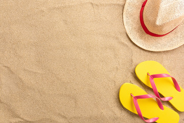 Fototapeta na wymiar Flip flops, straw hat, on sand background. Beach vacation concept .Top view with copy space.