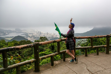 A girl with purple braids on her head waving a Brazilian flag.