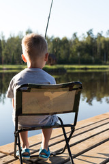 background. a boy with a fishing rod sits in a chair and catches a fish