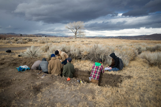 A diverse group of students in a soil science class studying a soil pit on a university field trip to the Great Basin Desert around Washoe County, Northern Nevada, USA.