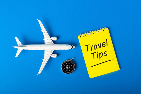 Travel Tips - notepad, compas and toy airplane on blue background. Summer travel concept 2020