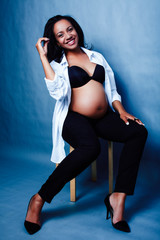 young pretty african american woman pregnant happy smiling, posing on blue background, lifestyle people concept copyspace