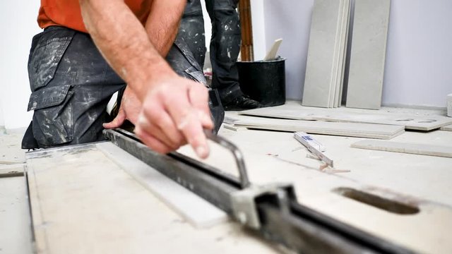 Handwerker schneidet grosse fliesen mit Fliesenschneider in einem neubau haus 4k Video in zeitlupe