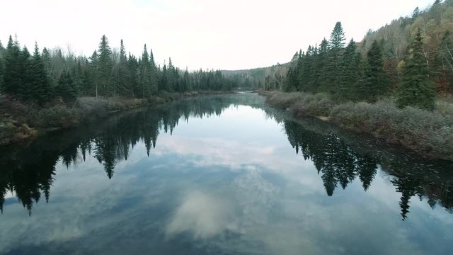 A vehicle passes near a calm river. Filmed in Quebec (Canada) during the autumn.