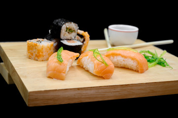 Close Up Of Various Types Of Japanese Fresh Prepared Sushi on wooden table on black isolated background .
