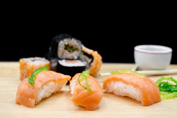 Close Up Of Various Types Of Japanese Fresh Prepared Sushi on wooden table on black isolated background .