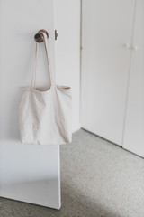 shopping and daily life, plain white canvas tote bag handging on door knob in front of wardrobe doors with minimalist look