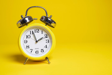 A yellow alarm clock on a yellow background