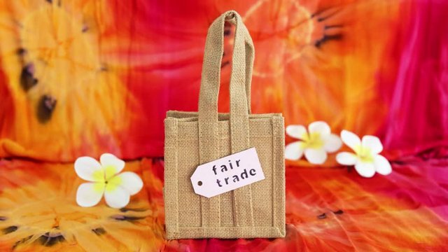 ethical shopping, bag made of natural materials with Fair Trade text on price tag on hippie tie dye background and camera defocusing