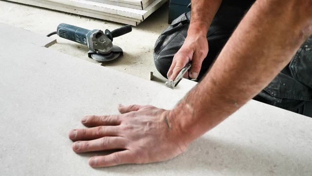 Fliesenleger schneidet fliesen mit einem winkelschleifer (flex) 4k video in zeilupe