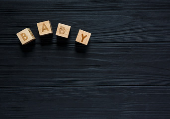 Wooden blocks with word Baby, toys for creativity  development on black background. Educational games for kindergarten, preschool kids. 