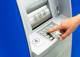 ATM machine close-up. male hand dials a password at an ATM. banking and finance concept. mockup, copy space