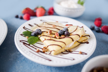 Crepes on a plate garnished with berries and mint
