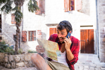 Handsome beard man talking on phone and using paper map in new town