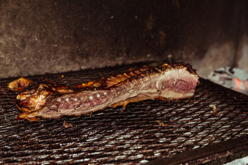 Traditional suckling pig cooked on the charcoal grill. The little pig is roasted whole on an open...