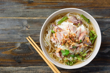 Rice noodles soup with beef in a bowl and chopsticks on wooden background, Asian food, Top view