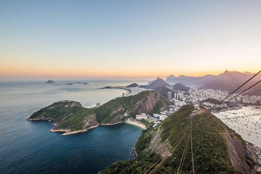 View from Sugarloaf mountain in Urca at sunset overlooking the city and mountains of Rio de Janeiro with Atlantic Ocean and boats in Guanabara bay down below in Rio, Brazil, South America