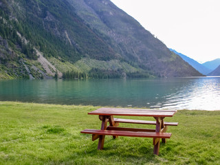 Naklejka na ściany i meble Picnic Table in Park with mountain lake background.